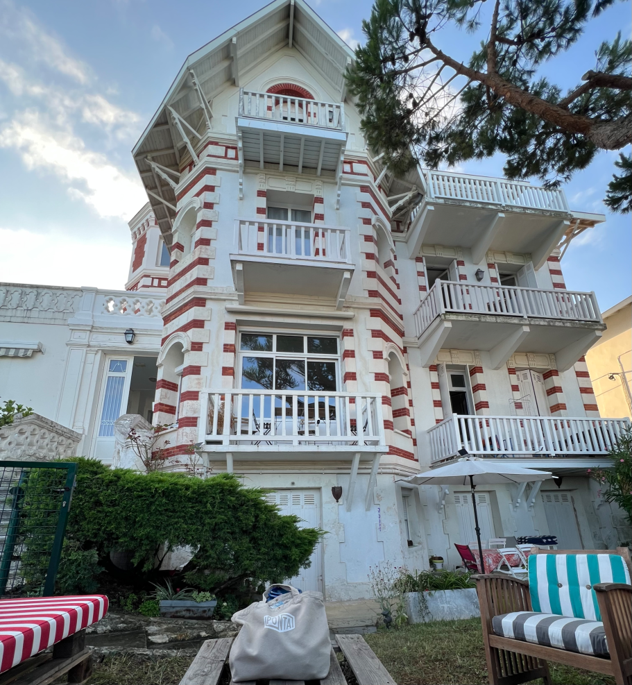 maison Maison à facade blanche et rouge avec balcons, située dans un jardin.
